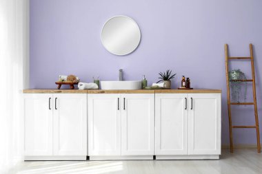 Ayna, banyo malzemesi ve lavabo olan çekmeceler. Banyonun iç tarafındaki leylak duvarın yanında.