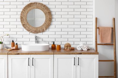 Lavabo, banyo malzemeleri çekmeceler, ayna ve raflar banyodaki beyaz tuğla duvar.