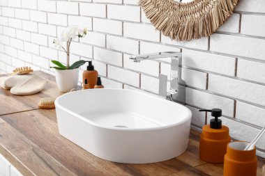 Lavabolu çekmeceler ve banyodaki beyaz tuğla duvarın yanında kozmetik ürünler.