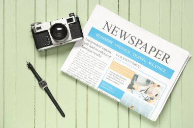 Renkli ahşap arka planda klasik fotoğraf makinesi, kol saati ve gazete