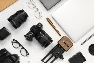 Profesyonel fotoğrafçı ekipmanları, modern dizüstü bilgisayar ve hafif arka planda gözlüklerle kompozisyon