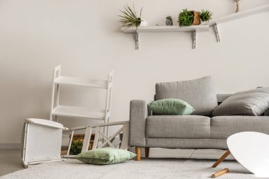 Kanepesi ve rafları olan dağınık bir oturma odası.