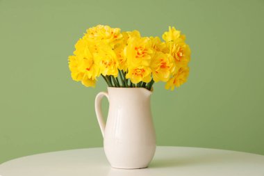 Nergis çiçekleri sehpanın üzerinde yeşil arka planda.