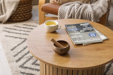 Oturma odasındaki masada çay ve dergilerle Tibet şarkı kasesi, yakın plan.