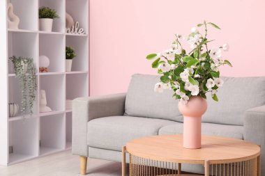 Rahat kanepesi, sehpası ve çiçek açan ağaç dalları olan şık bir oturma odası.