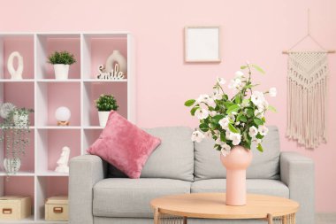 Rahat kanepesi, sehpası ve çiçek açan ağaç dalları olan şık bir oturma odası.