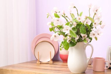 Çiçek açan dalları ve mutfak tezgahında tabakları olan vazo.