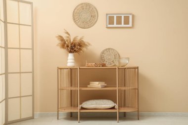 Bej duvarın yanında farklı dekorları olan ahşap raf ünitesi.