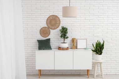 Beyaz tuğla duvarın yanında farklı dekorları olan beyaz ahşap dolap.