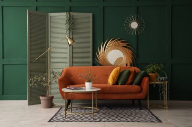 Yastıklı rahat bir kanepe, dergisi olan bir sehpa ve oturma odasında bitki.