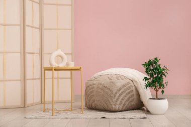 Pouf, çiçek ve kahve masası oturma odasında.