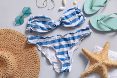 Gri arka planda mayolu ve plaj aksesuarlı güzel kompozisyon