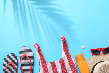 Mavi arka planda plaj aksesuarları ve güneş kremi