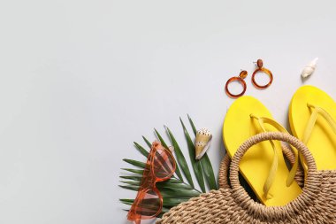 Plaj aksesuarları ve gri arka planda palmiye yaprağı olan güzel bir kompozisyon.