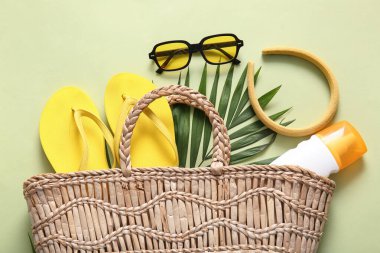 Plaj aksesuarları, güneş kremi ve yeşil arka planda saç bandı olan güzel bir kompozisyon.