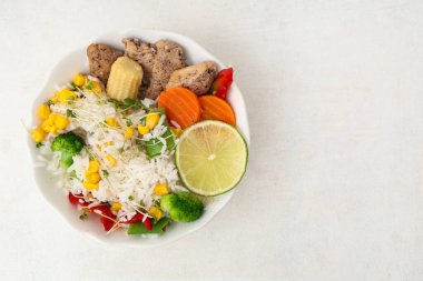 Sebzeli bir kase lezzetli pilav ve arka planda tavuk.