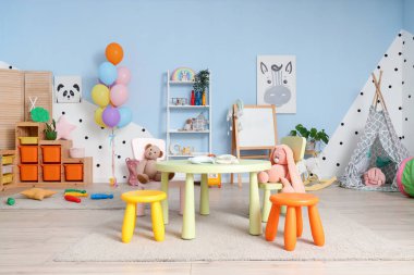 Anaokulundaki modern oyun odasının içinde masa, sandalye ve oyuncaklar var.