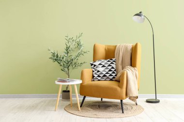 Oturma odasında yastıklı, ekoseli, lambalı, çiçekli ve kahve masalı bir koltuk.