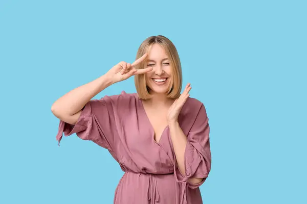 stock image Beautiful young woman with bob hairstyle showing victory gesture on blue background