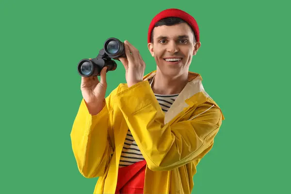 stock image Young sailor in raincoat with binoculars on green background