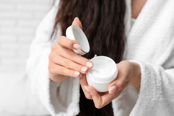 Женщина в халате с банкой натурального крема, крупным планом