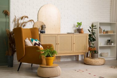 Oturma odasının içinde raf ünitesi, çekmeceler ve koltuk var.