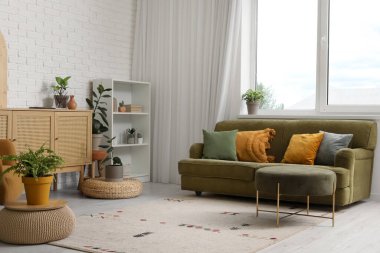 Oturma odasında rahat bir kanepe, raf ünitesi ve çekmeceler var.