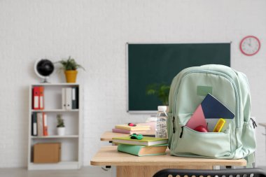 Sınıfta masanın üzerinde kitap ve su şişesi olan bir sırt çantası.