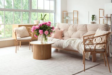 Koltuklar, kanepe ve oturma odasının içinde şakayıklar olan kahve masası.