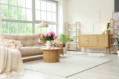 Oturma odasındaki çekmecelerin yanındaki sehpanın üzerinde güzel şakayık çiçekleri olan vazo.