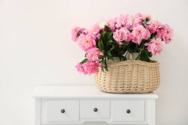 Tuvalet masasında şakayık çiçekleri olan hasır sepet.