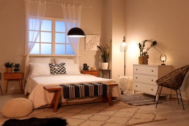 Modern yatak odasının içinde parlayan lambalar olan rahat bir yatak.