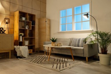 Rahat kanepesi, sehpası ve parlak lambaları olan şık bir oturma odası.