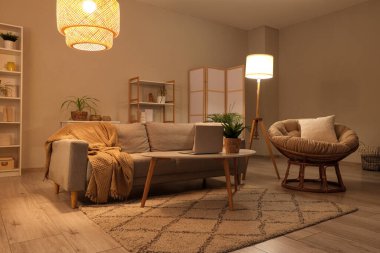 Kanepesi, koltuğu, laptoplu sehpası ve parlak lambaları olan şık bir oturma odası.