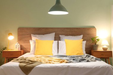 Yatak odasının içinde rahat yataklar, komodinlerin yanında parlayan lambalar.