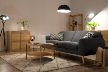 Rahat kanepesi, masası, modern dizüstü bilgisayarı ve parlayan lambaları olan bir oturma odası.