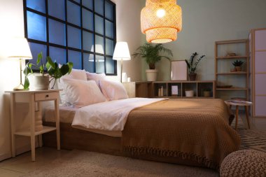 Yatak odasının içinde rahat bir yatak odası, raf ünitesi ve parlayan lambalar.