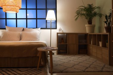 Yatak odasının içinde rahat yatak odası, askı ve parlak lambalar var.