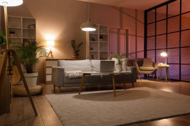 Sofra, modern dizüstü bilgisayarlı masa ve oturma odasının içinde parlayan lambalar.