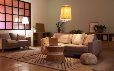 Kanepeleri, masası ve parlayan lambaları olan rahat bir oturma odası.