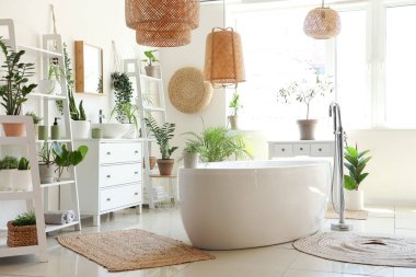 Küvet, raf üniteleri, çekmeceler ve modern banyonun penceresinin yanındaki farklı ev bitkileri.