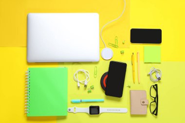 Sarı arka planda farklı modern cihazlar ve kırtasiye malzemeleriyle kompozisyon