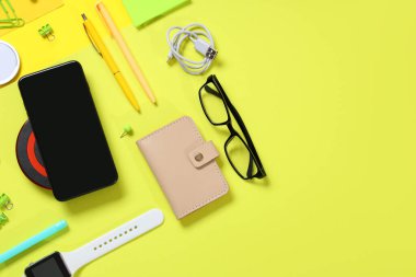 Sarı arka planda farklı modern cihazlar ve kırtasiye malzemeleriyle kompozisyon