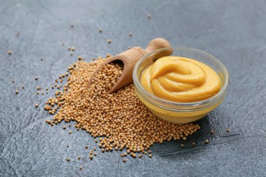 Kremalı hardallı kase ve siyah grunge arka planda tohumlar.