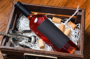 Kahverengi ahşap arka planda şarap ve tirbuşon dolu bir kutu.