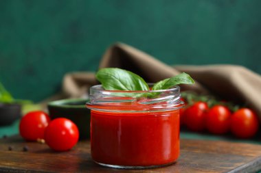 Yeşil arka planda fesleğenli domates sosu kavanozu