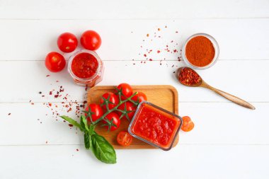 Cam kase ve beyaz ahşap arka planda fesleğenli domates sosu.