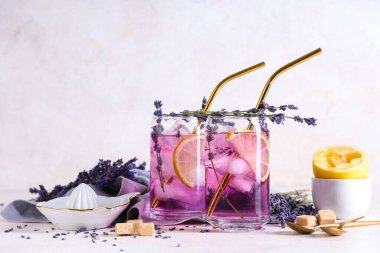 Beyaz arka planda çiçekler ve meyve sıkacağıyla taze lavantalı limonata.