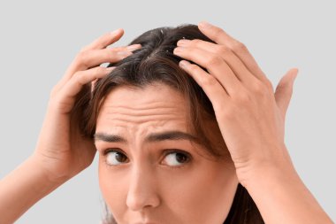 Hafif arka planda kepekli endişeli genç kadın, yakın plan.