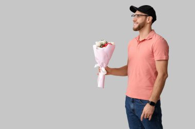 Gri arka planda güzel lalelerle dolu buketi olan mutlu teslimatçı.